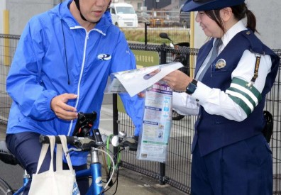 自転車利用者に道交法改正を周知する警察官＝１日、鹿児島市のＪＲ谷山駅