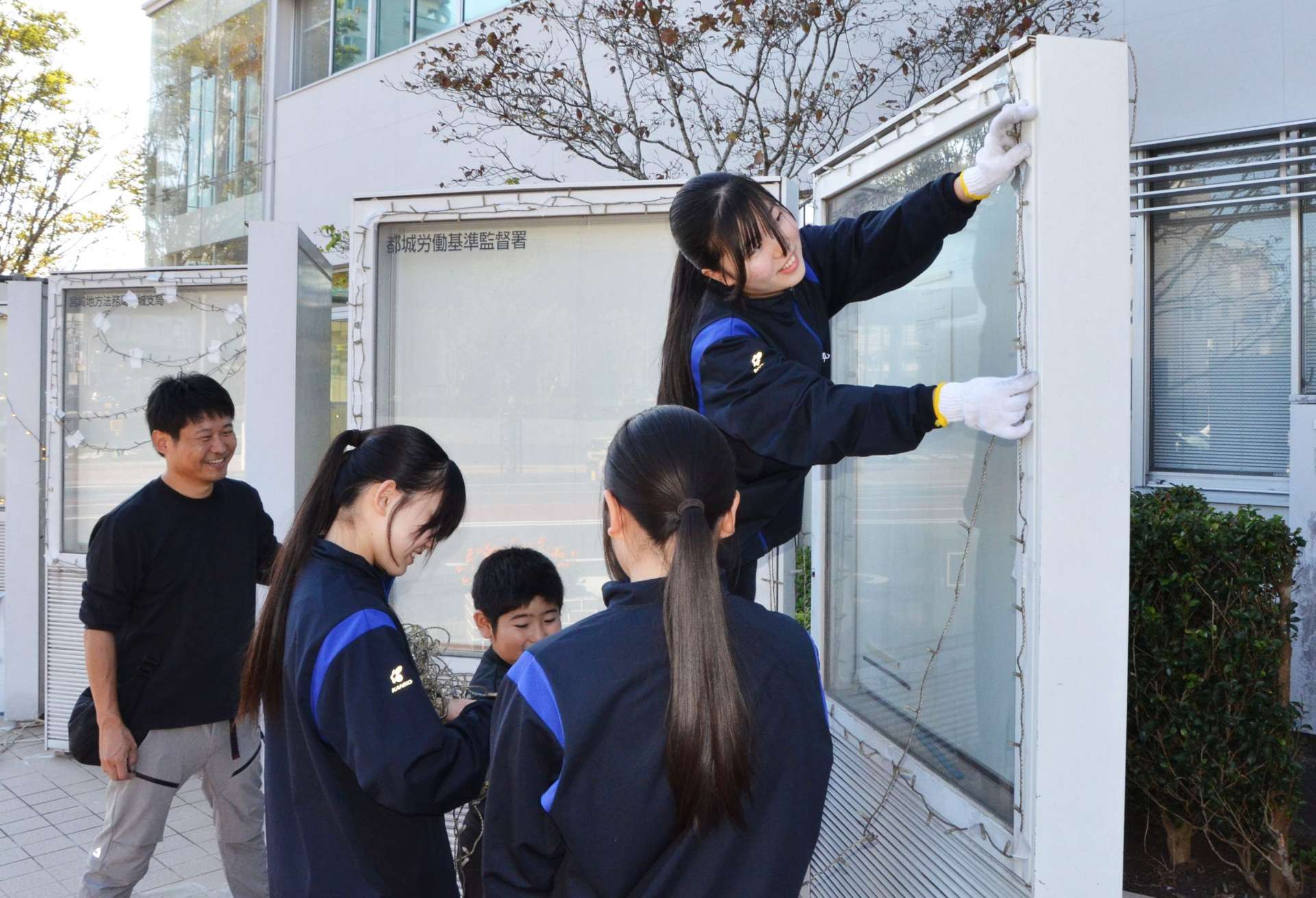 都城合同庁舎の掲示板に電飾を設置する都城泉ケ丘高校生＝都城市上町