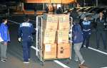 トラックから降ろされた資機材を運ぶ作業員ら＝１９日午後７時２１分、出水市高尾野町大久保