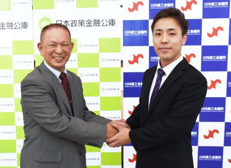 成約式で握手する山本和幸さん（左）と田ノ上崚さん＝２１日、薩摩川内市の川内商工会議所