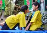 四つんばいになって、駆け引きしながら長餅を引っ張り合う子どもたち＝日置市伊集院町古城の大山祇神社