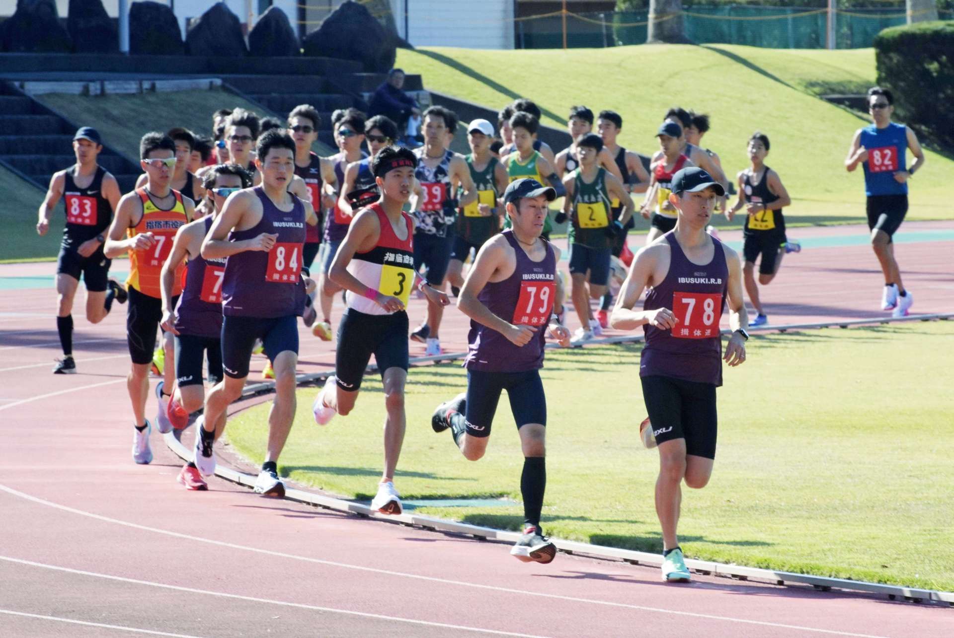 スタートし集団で駆け抜ける指宿会場の選手たち＝指宿市営陸上競技場