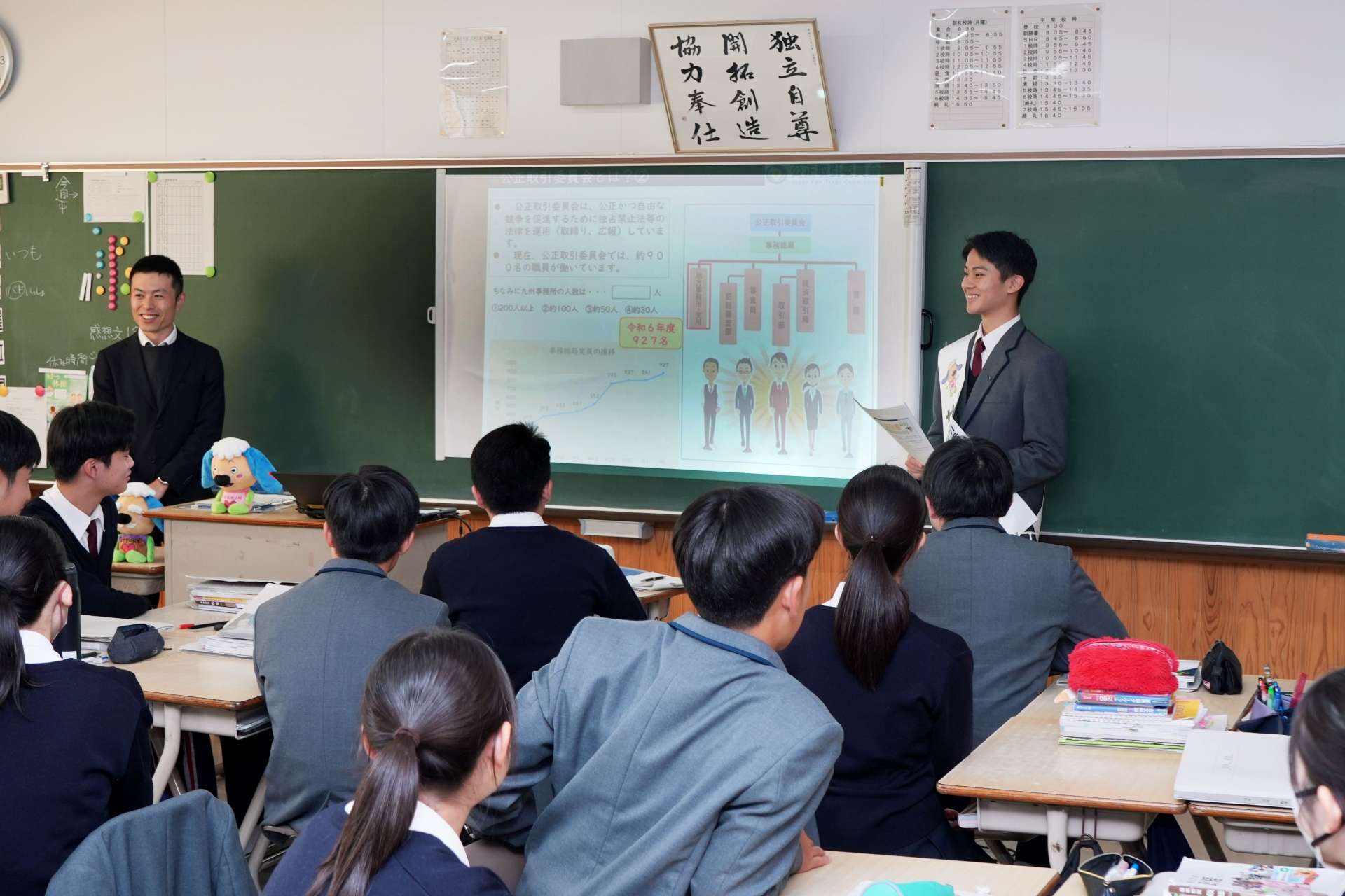 公正取引委員会について説明するサポーターの中園秀真さん（右）＝６日、鹿児島市谷山中央８丁目の鹿児島南高校