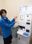 設置された自動外貨両替機を前に「多くの人に利用してもらえれば」と話す職員＝１８日、志布志市のサンポートしぶしアピア