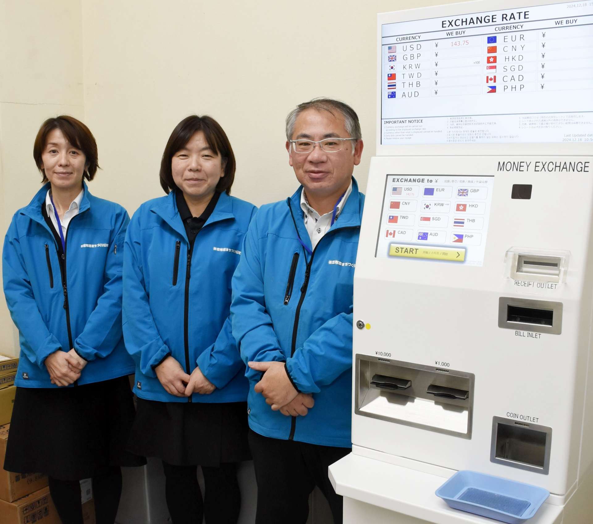 自動外貨両替機の横で「多くの人に利用してもらえれば」と話す職員＝１８日、志布志市のサンポートしぶしアピア