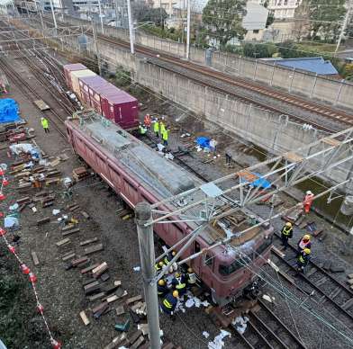 〈別カット〉機関車と貨車の復旧作業に当たる作業員ら＝１８日午後４時５０分ごろ、薩摩川内市