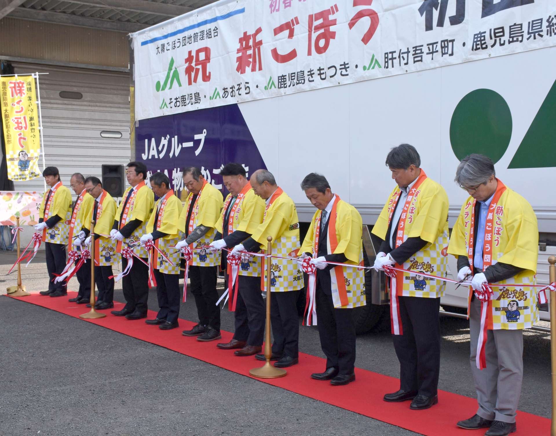新ゴボウの出荷を祝いテープカットする関係者＝２０日、志布志市のＪＡ県経済連大隅野菜事業所