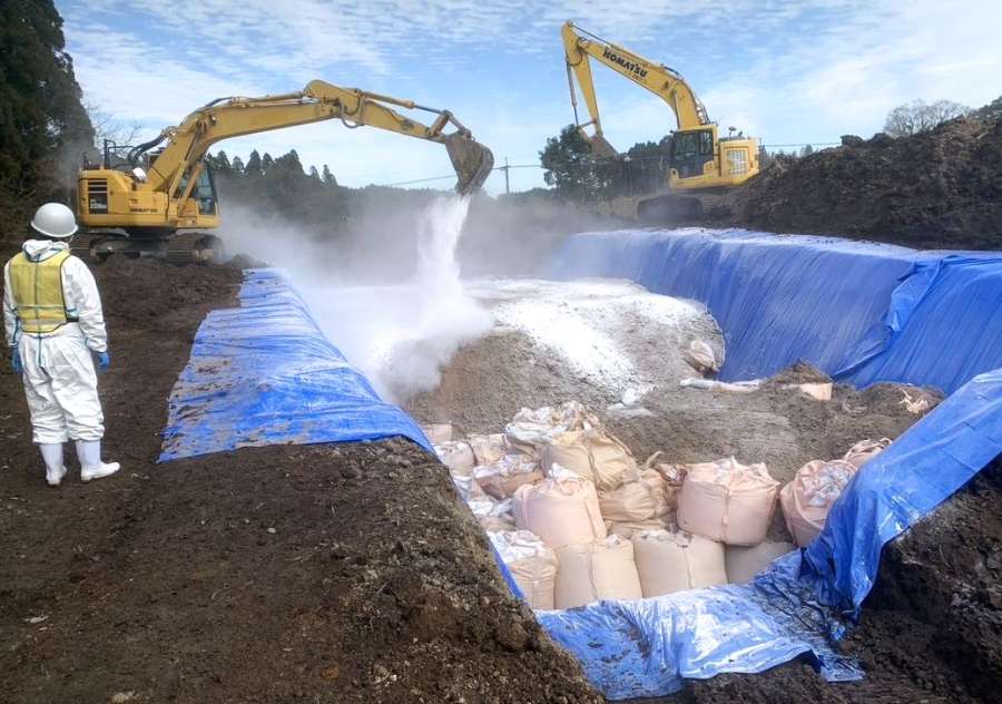 殺処分した鶏などを埋め終えた埋却地に消石灰をまく鹿児島県職員ら＝２３日、霧島市（県提供）