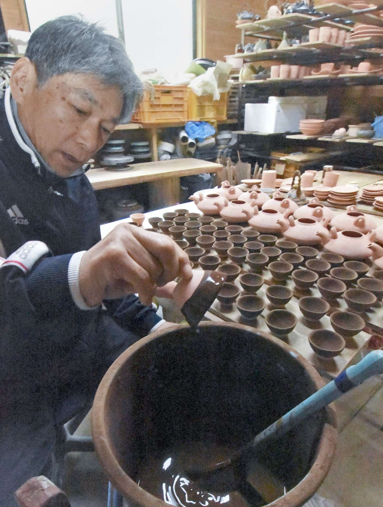 杯に釉薬をかけ初窯展へ準備する東祐一さん＝南さつま市の笠沙陶苑