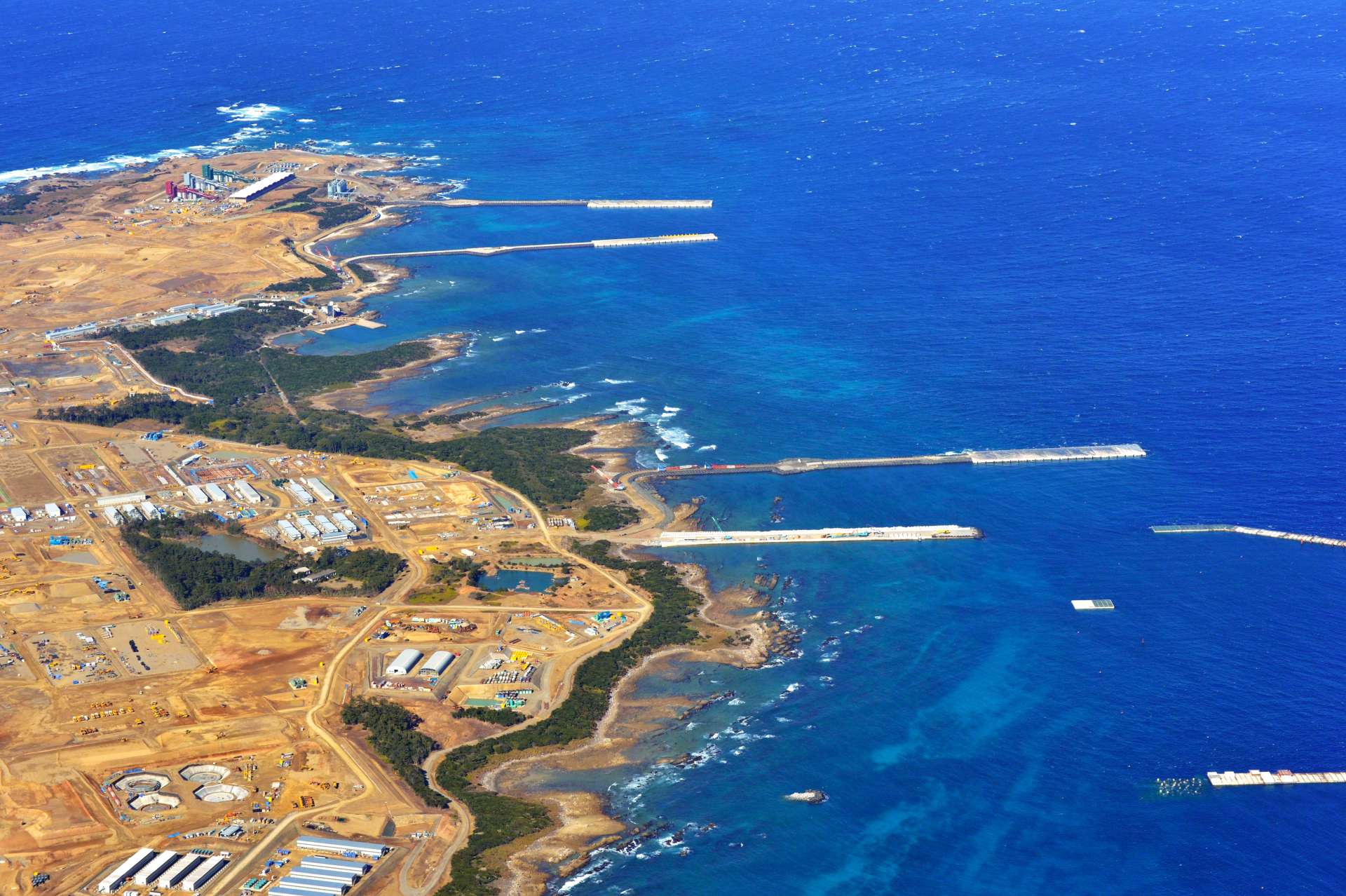 南側方向から撮影した島の北東部。東側に延びる上から３本が仮設桟橋＝１０日、西之表市の馬毛島上空