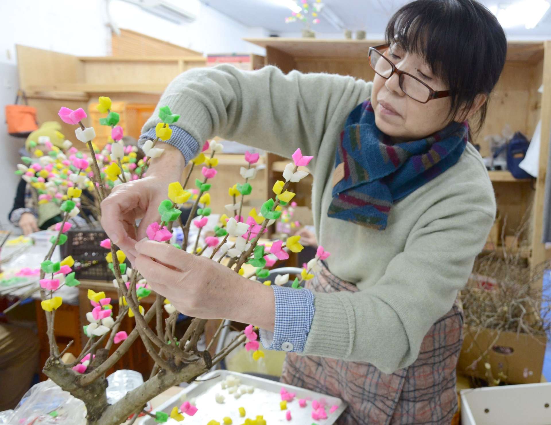 色とりどりの餅を枝に付ける女性＝奄美市名瀬の中原商店