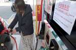 値上げを前にガソリンを給油する女性客＝１４日、鹿児島市のセルフステーション南林寺
