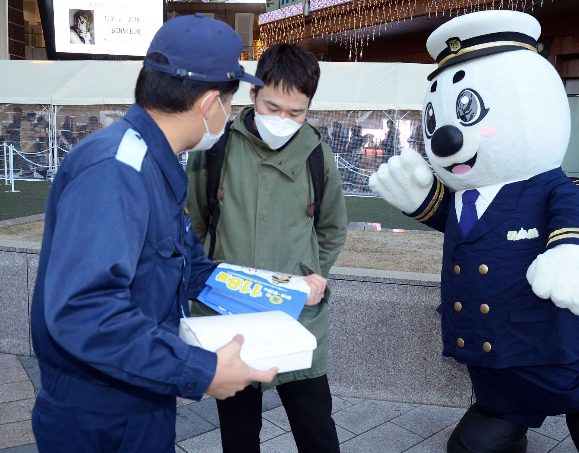 １１８番をＰＲする海上保安庁のマスコット「うみまる」と海上保安官＝１７日、鹿児島市のＪＲ鹿児島中央駅