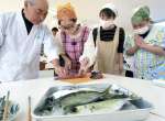 プロの指導でブリやアジをさばく保護者＝南さつま市の金峰学園