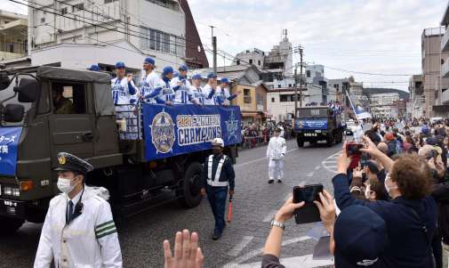 沿道の市民らに手を振る選手＝１日、奄美市名瀬