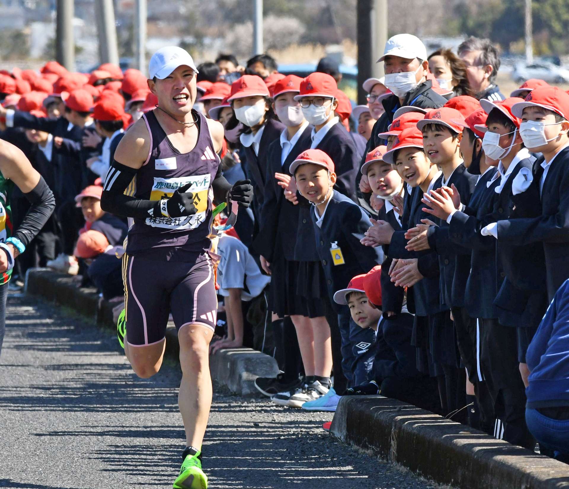 子どもたちの声援を受け、中継所に向かう曽於の大野勝太選手＝１９日午後、霧島市国分福島