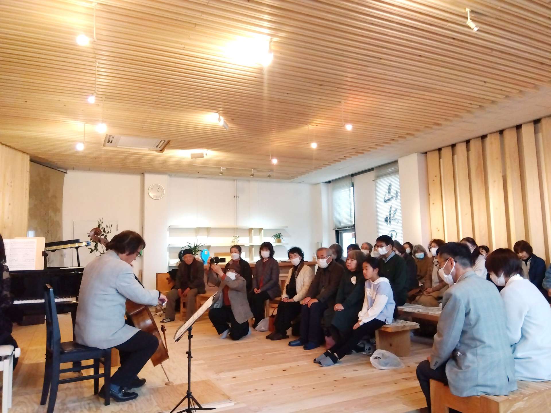 ヒノキがふんだんに使われた真新しい音楽ホールで土田浩さんのチェロ演奏を楽しむ人たち＝えびの市向江