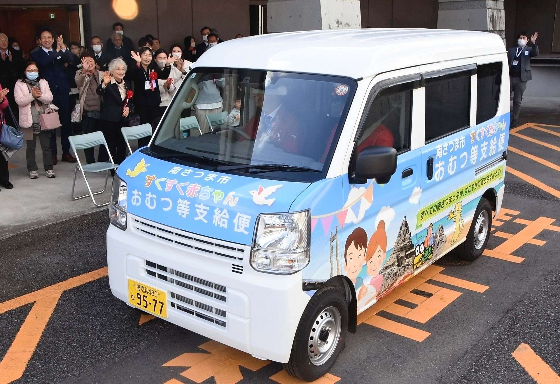 出発式で宅配の専用車を見送る関係者＝１９日、南さつま市加世田