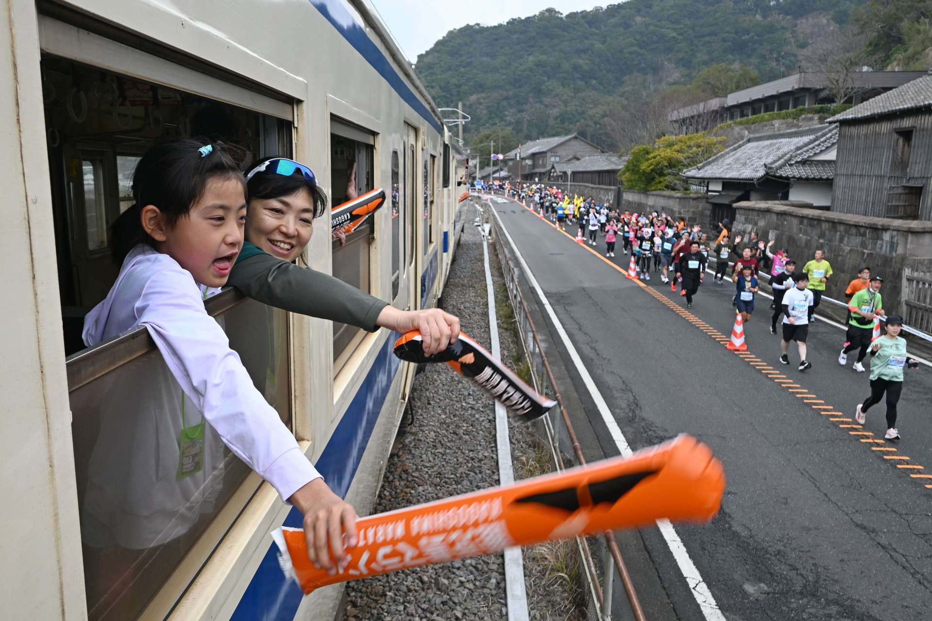 停止した車両からランナーに声援を送るツアー参加者＝２日、鹿児島市吉野町