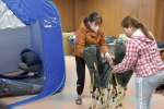 避難所内で使うテントやベッドを組み立てる参加者ら＝長島町役場指江庁舎