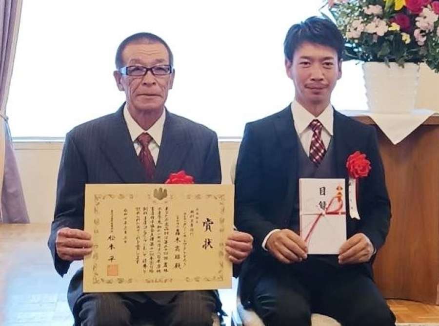 農林水産省畜産局長賞を受賞したグリーンネットワークとどろきの轟木高昭さん（左）＝３日、東京（鹿児島県提供）