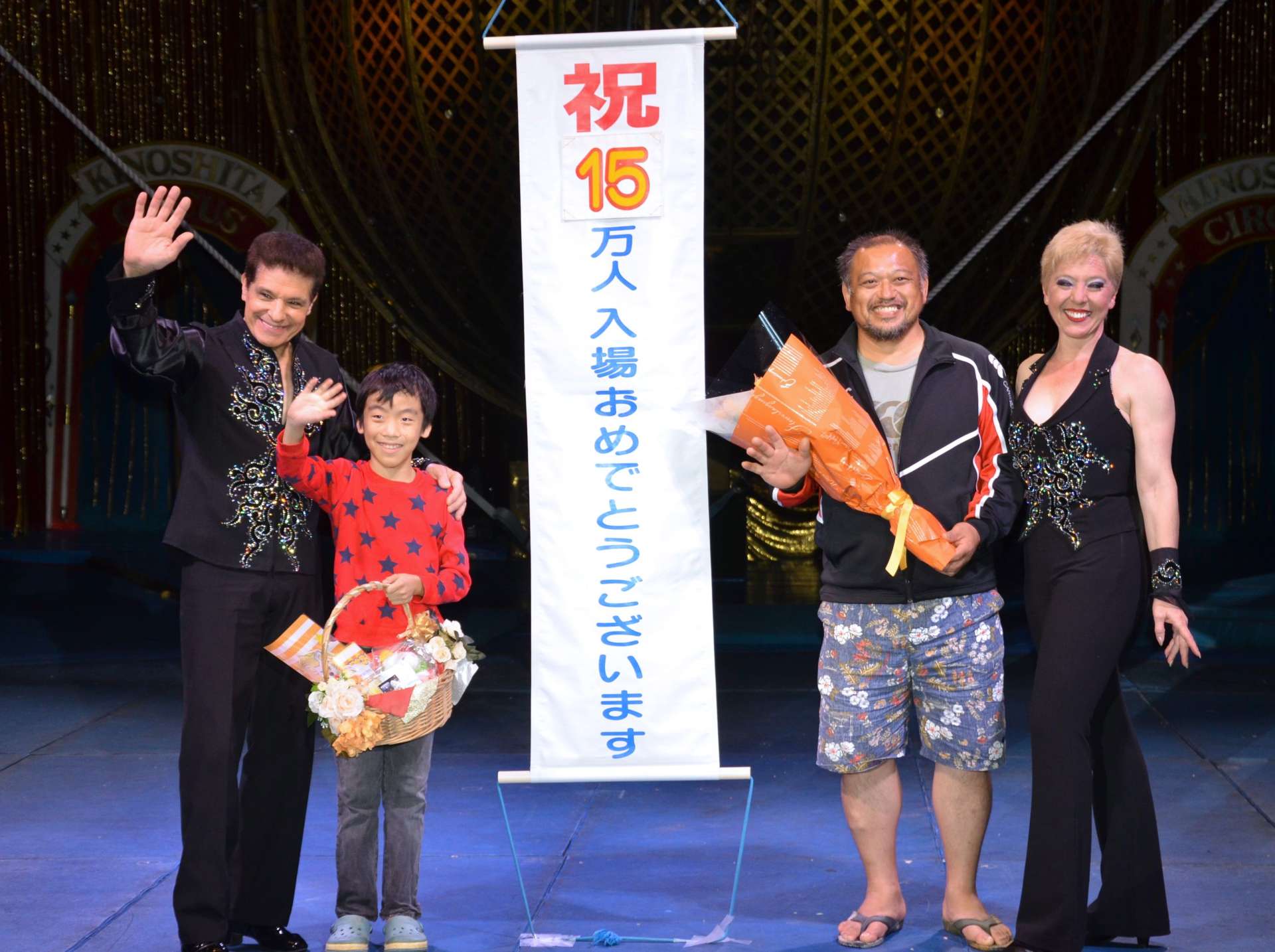 入場１５万人目の記念品を受け取る溝口志桜さん（左から２人目）と父・栄作さん（同３人目）＝３日、鹿児島市のドルフィンポート跡地