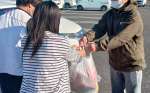 かごしまおもいやりネットワーク事業で法人担当者（右）から食料の現物支給を受ける相談者（県社会福祉法人経営者協議会提供）