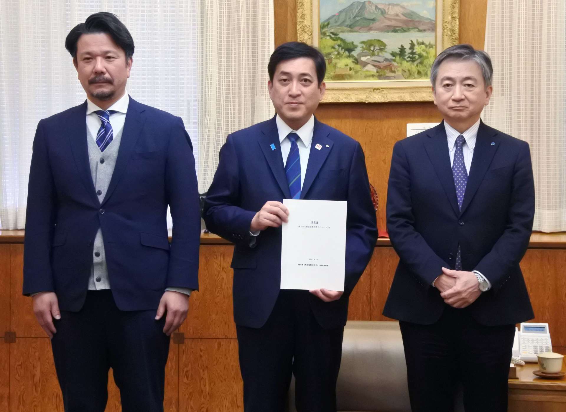 塩田康一知事に提言書を提出した津曲貞利座長（右）と松田忠大委員＝７日、県庁