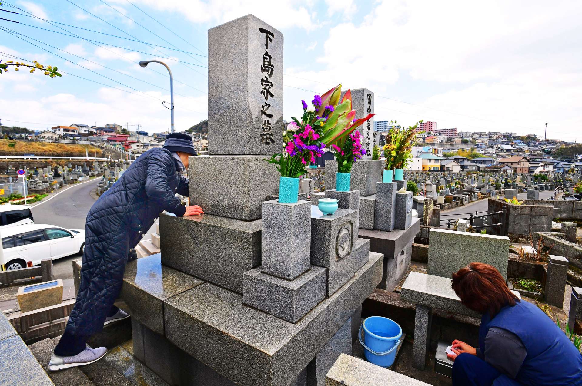 先祖の墓を訪れ、手を合わせる親子連れ＝１７日午後、鹿児島市の坂元墓地
