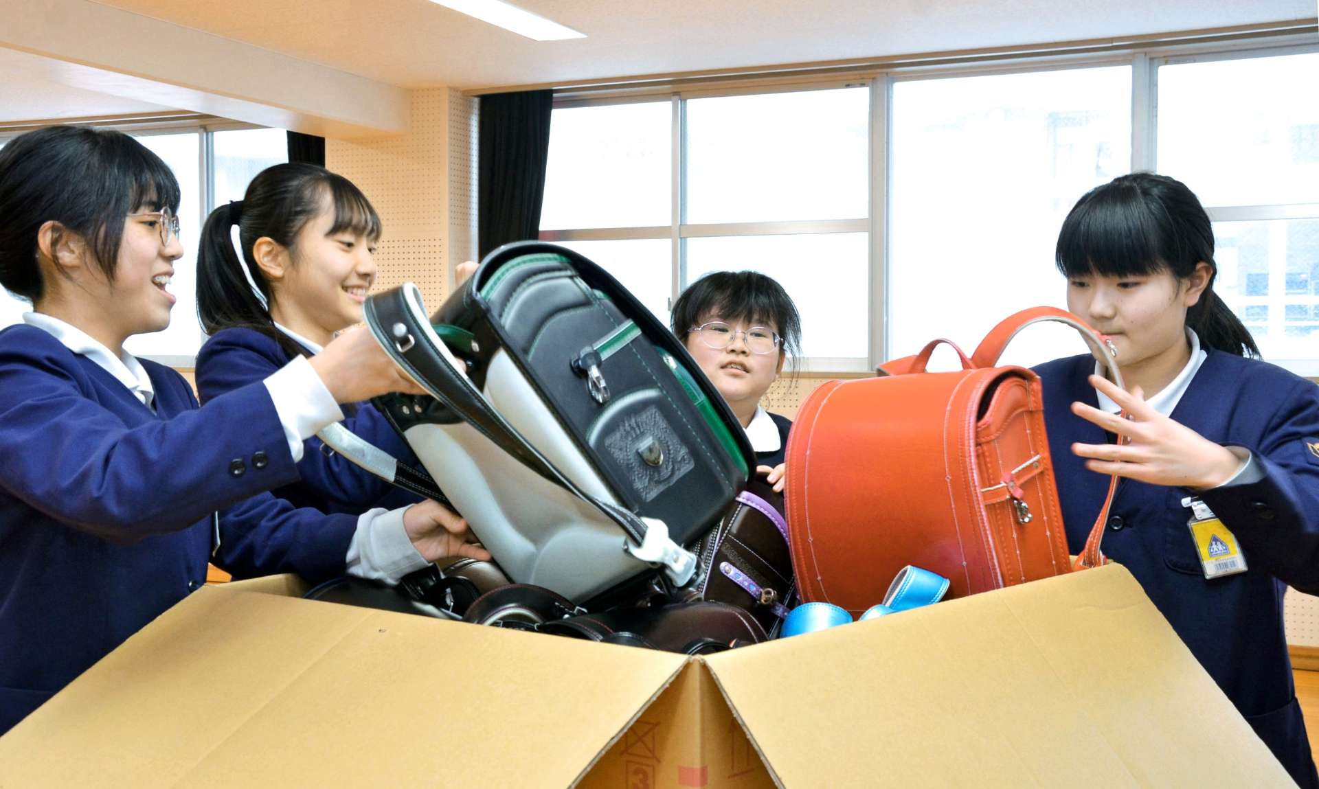 思い出の詰まったランドセルを発送用の段ボールに入れる実行委員＝１７日、鹿児島市の広木小学校