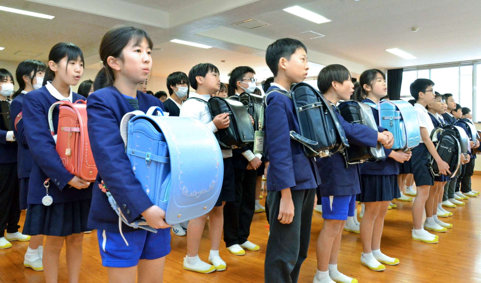 思い出の詰まったランドセルを抱え合唱する６年生＝１７日、鹿児島市の広木小学校