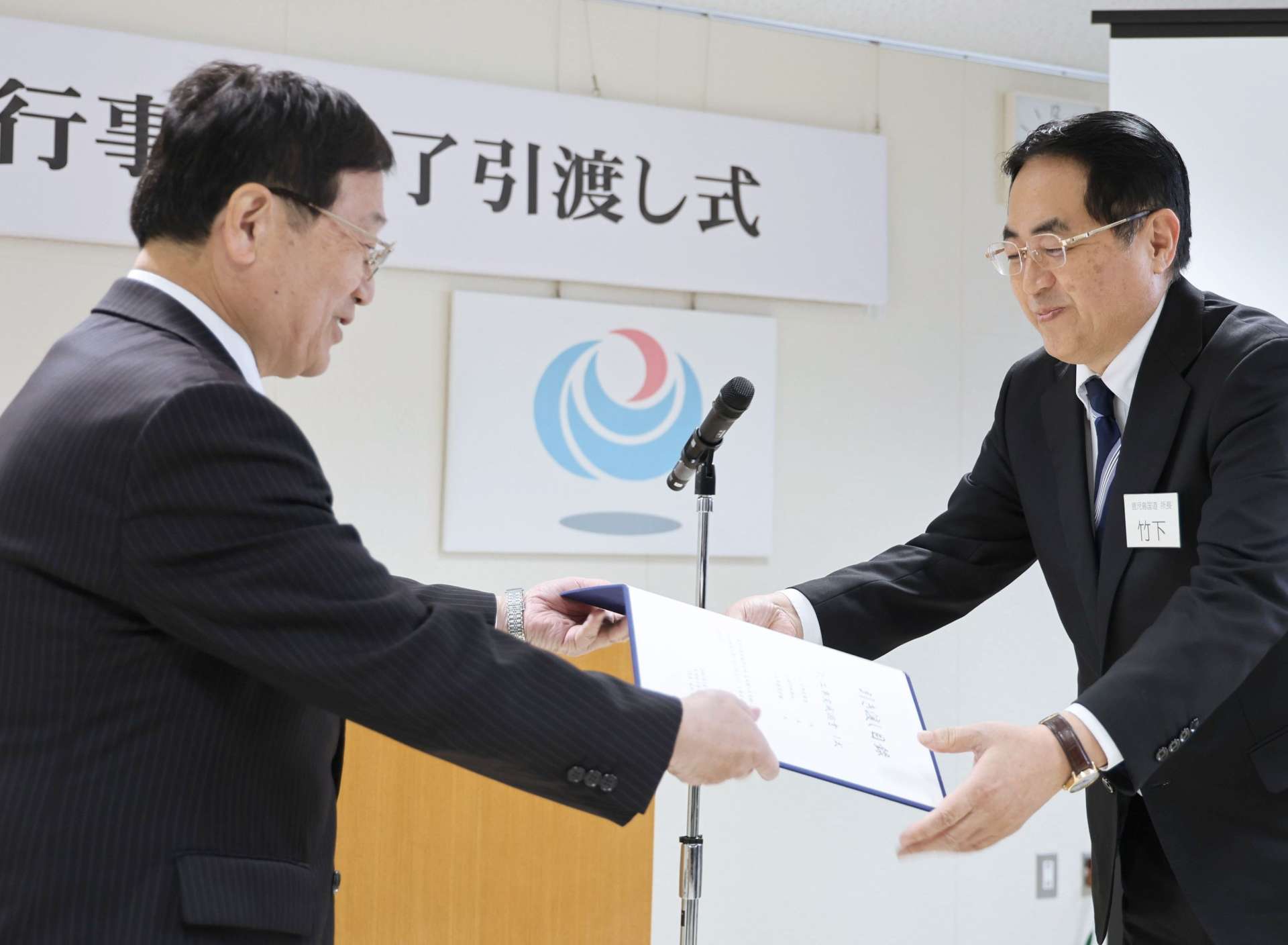 竹下卓宏鹿児島国道事務所長（右）から引き渡し書を受ける田中良二市長＝１９日、薩摩川内市役所
