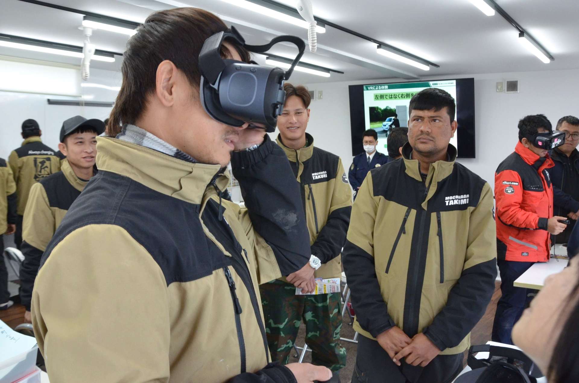 ＶＲゴーグルを着け、自転車の危険運転を疑似体験する外国人労働者＝都城市早鈴町