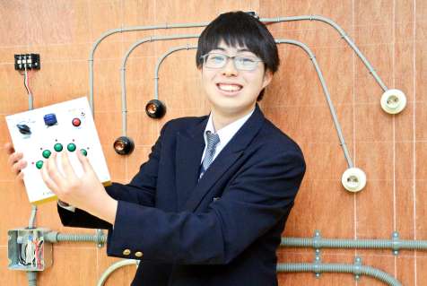 開発した「指のリハビリゲーム機」を手に笑顔を見せる尾辻佑樹さん＝鹿児島市の鹿児島情報高