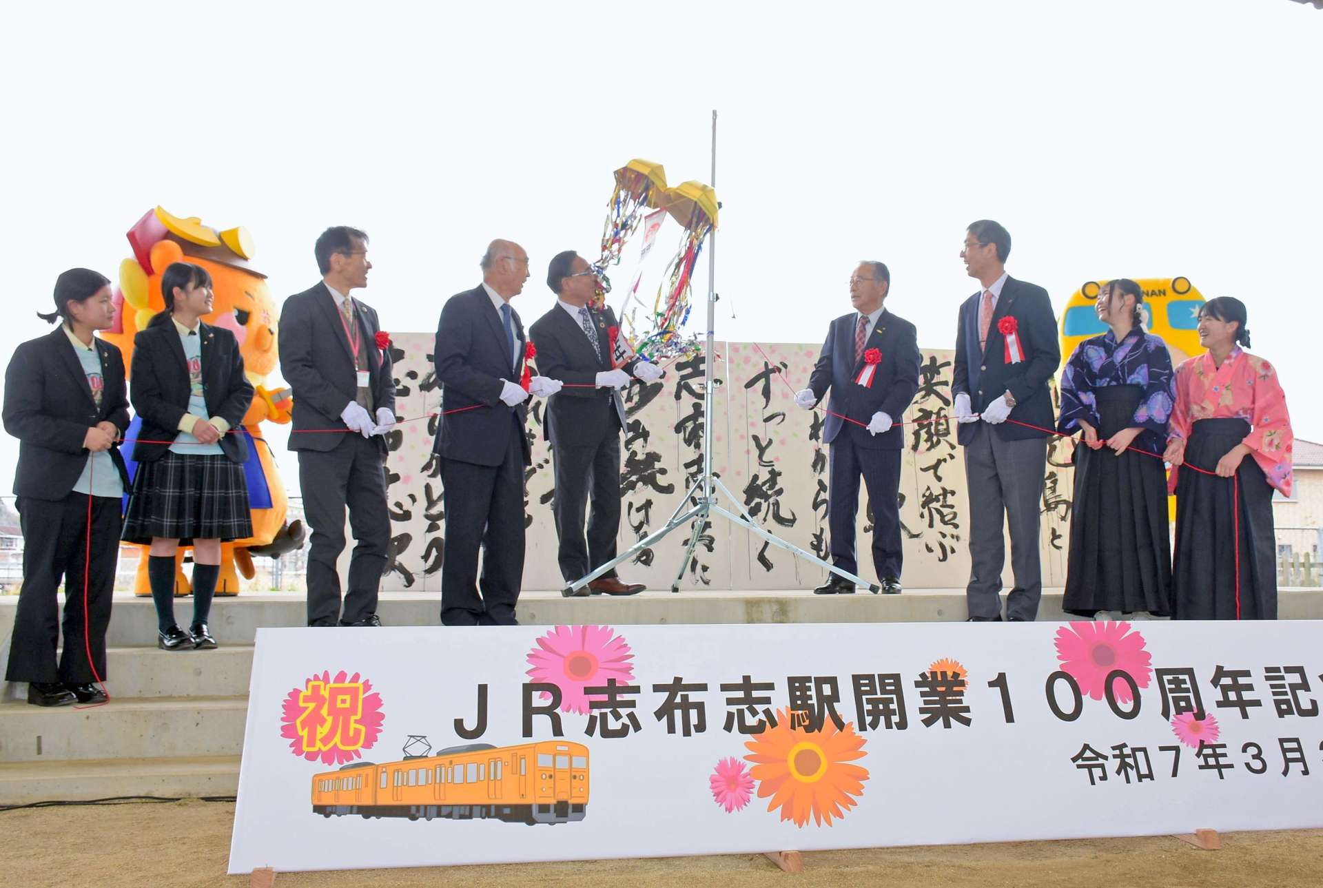 くす玉を割り、ＪＲ志布志駅開業１００年を祝う関係者＝３月３０日、志布志市の多目的イベント広場