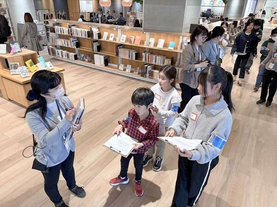 職員の案内で図書館を見学する小学生＝３月２９日、鹿児島市の天文館図書館
