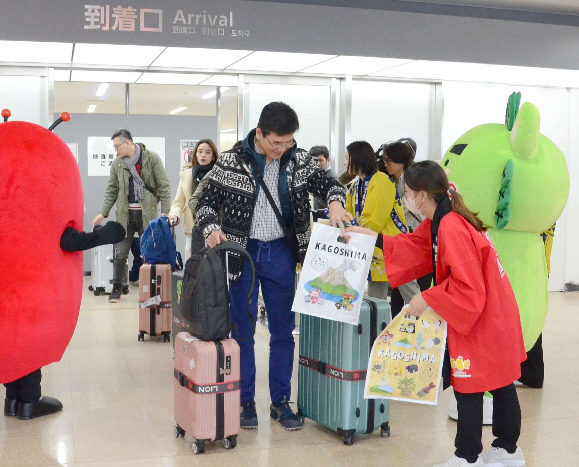 歓迎を受け、鹿児島の特産品が入った袋を受け取る台湾からの乗客＝３日、霧島市の鹿児島空港国際線ターミナル