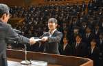 地頭所恵教育長から代表で辞令を受け取る新規採用教諭＝１日、鹿児島市のカクイックス交流センター
