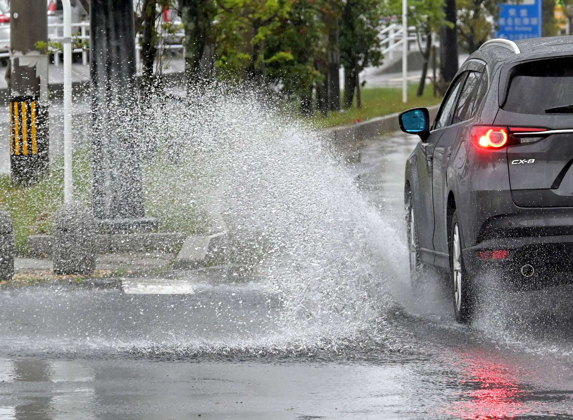 雨で冠水した道路を水しぶきを上げ走る車＝１０日午前９時４０分、鹿児島市住吉町