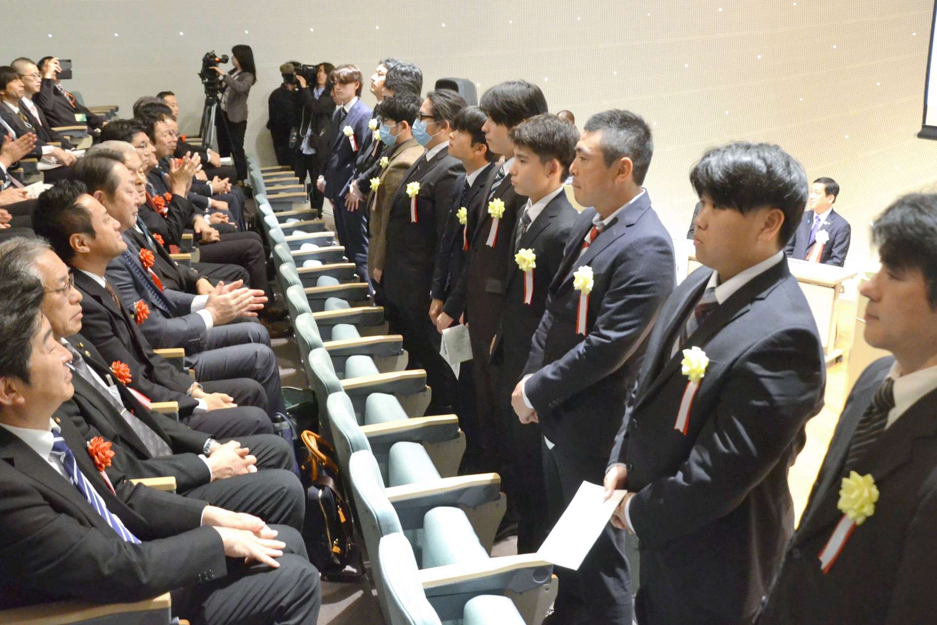 関係者に祝福される「かごしま林業大学校」の入講生１３人（右）＝１０日、鹿児島市の鹿児島大学稲盛会館