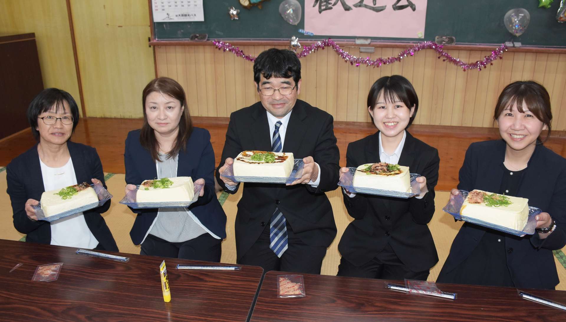 巨大な豆腐で歓迎される野神小の先生たち＝１１日、志布志市有明の野神青少年館