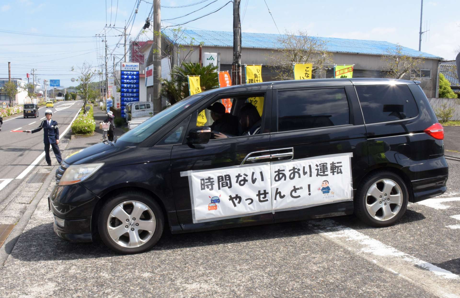 側面に標語を貼った車でスタートする参加者＝１３日、指宿市の指宿警察署