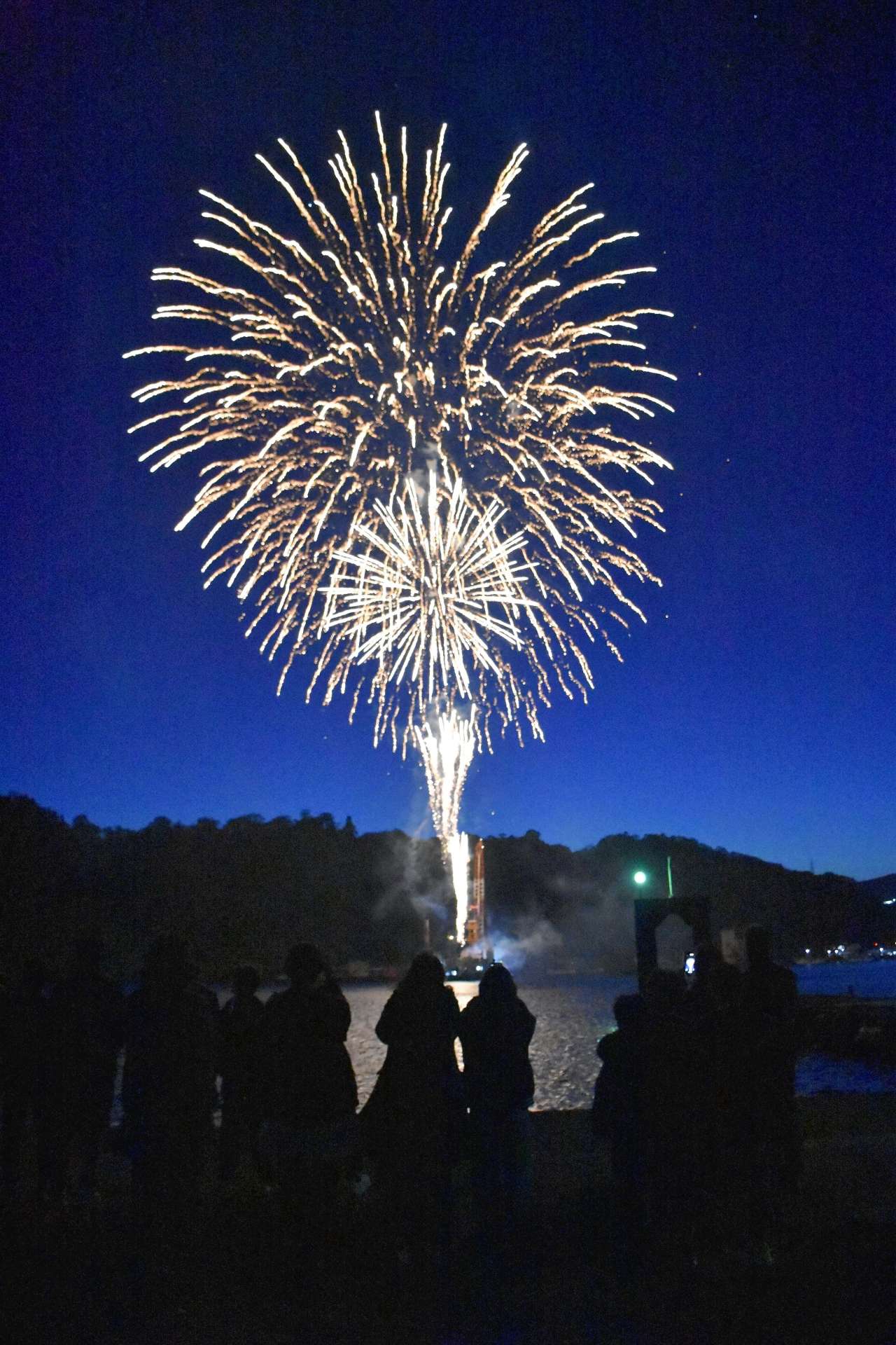 海上から打ち上げられ、春の夜空を彩る花火＝１５日、指宿市の山川漁港