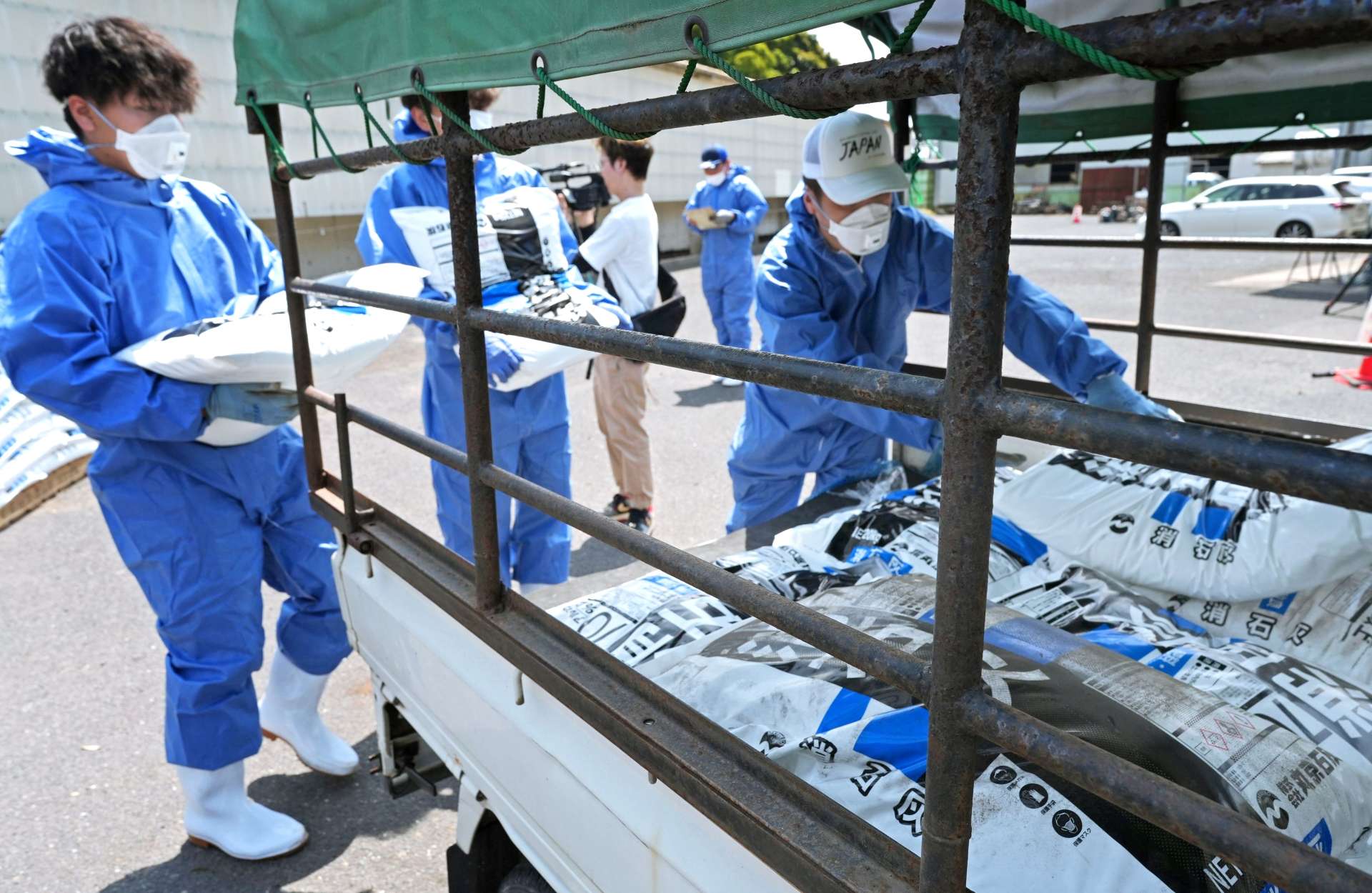 消石灰を軽トラックに積み込む市職員ら＝１７日、鹿屋市祓川町の市畜産環境センター
