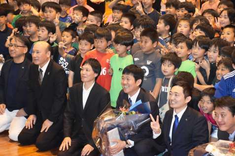花束手に子どもたちと記念写真を撮る森保一監督＝２７日、奄美市笠利