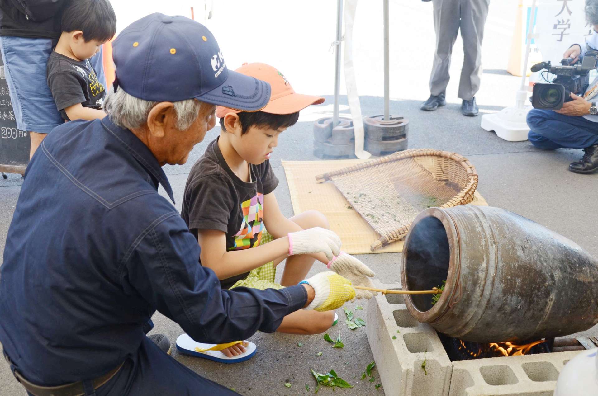 陶器のかめ（はんず）で茶の葉をいり蒸す「はんず茶」づくりを体験する子供ら＝４日、鹿児島市のおいどん市場与次郎館