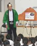 紙芝居で「宝暦治水」を伝える平田靱久さん＝鹿屋市の寿小学校