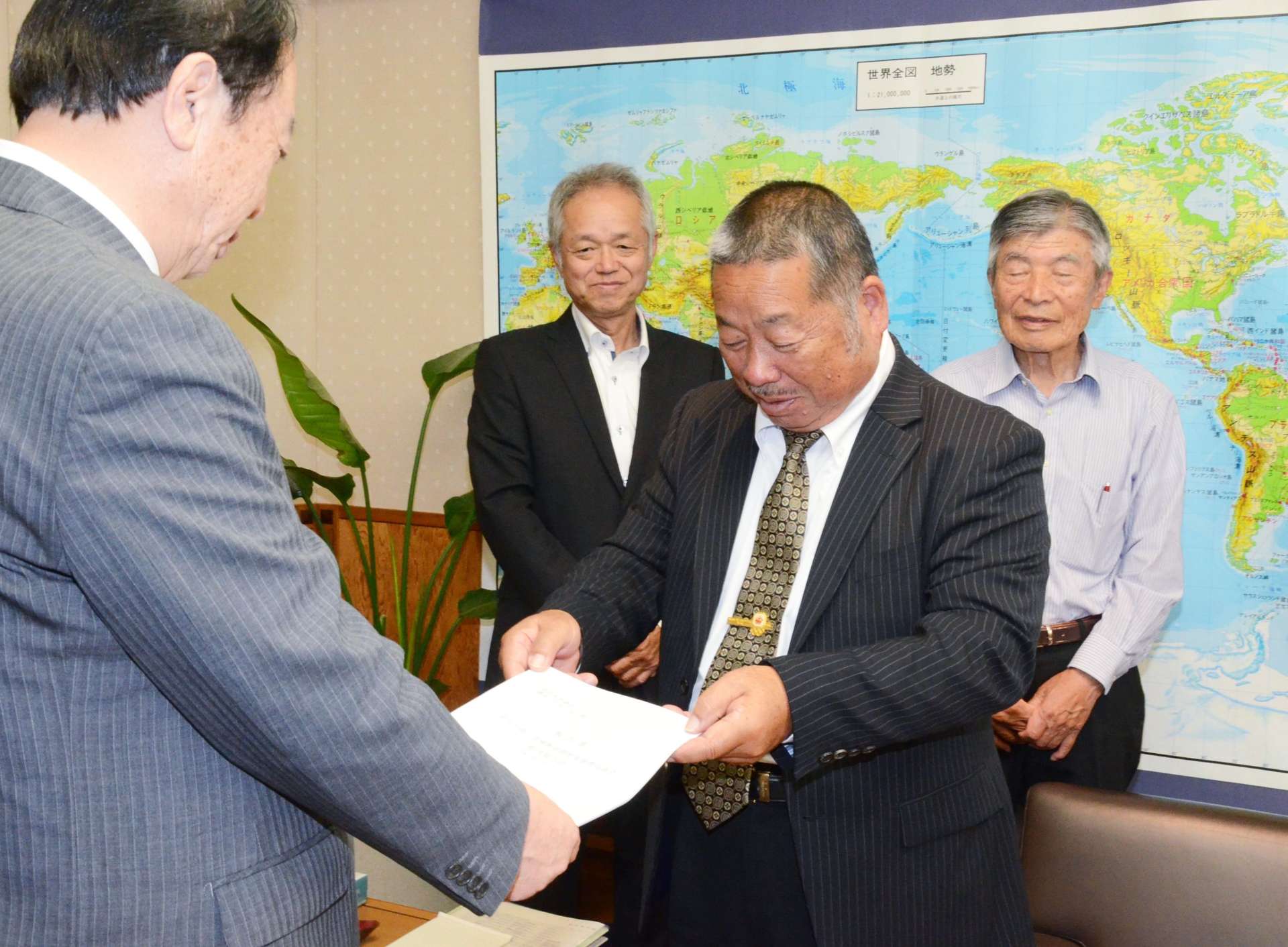 日高滋議長（左）に決起大会の報告書を手渡す磯辺昭信会長＝８日、県議会