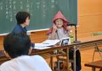 防空ずきんをかぶり、戦時中の体験を語る宮原アイさん＝２３日、霧島市の牧園中学校