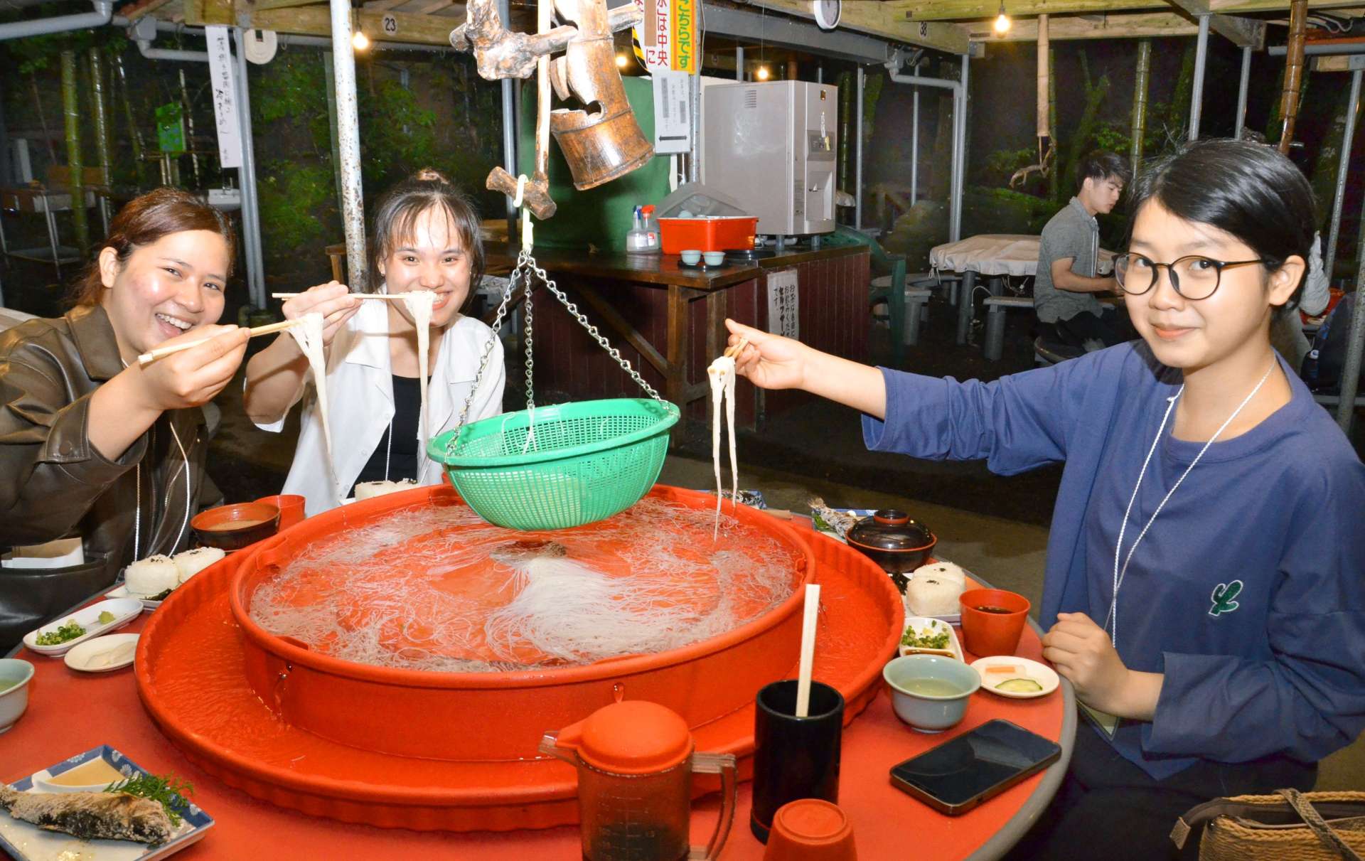 笑顔でそうめんを味わう外国人留学生ら＝２４日、鹿児島市の慈眼寺公園そうめん流し